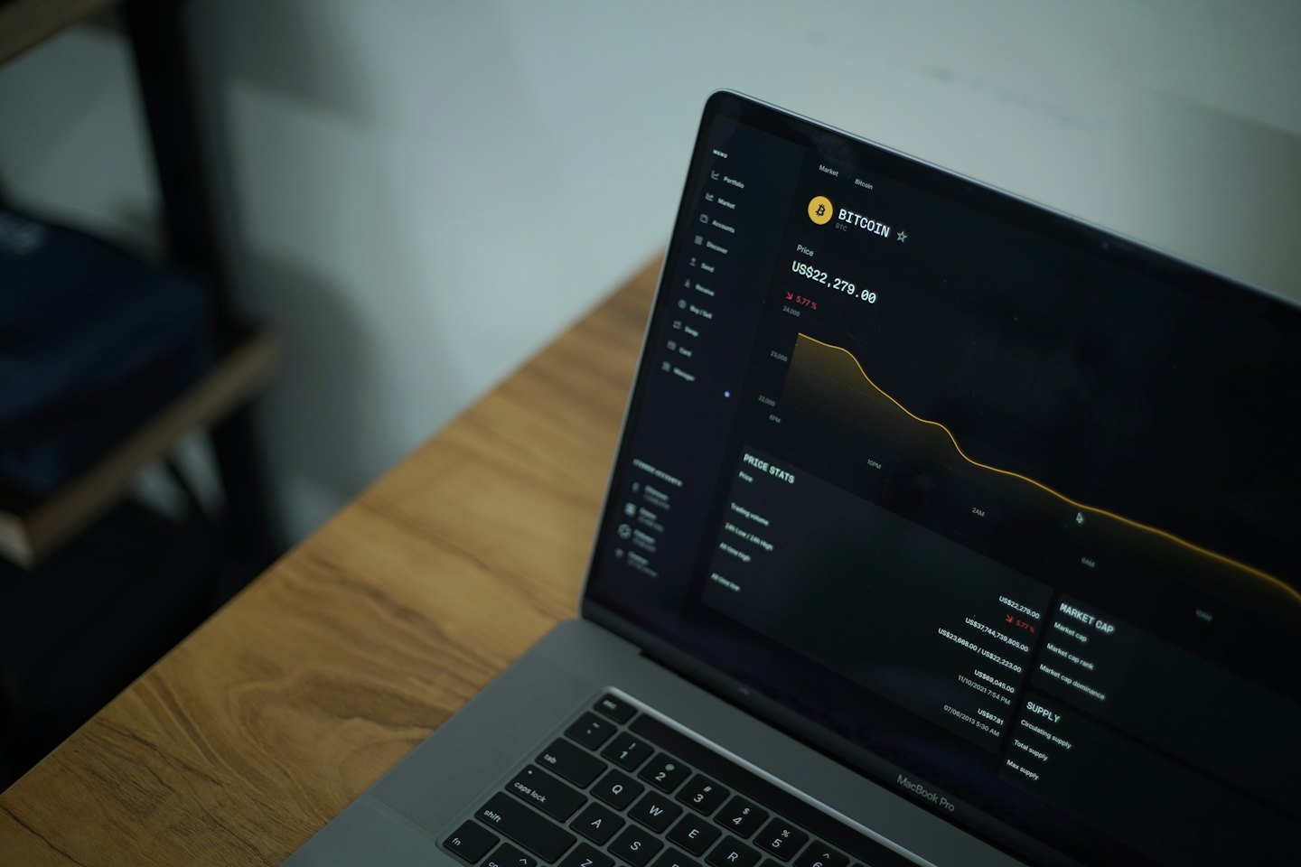 Laptopscherm toont cryptohandelsgegevens op een houten bureau.
