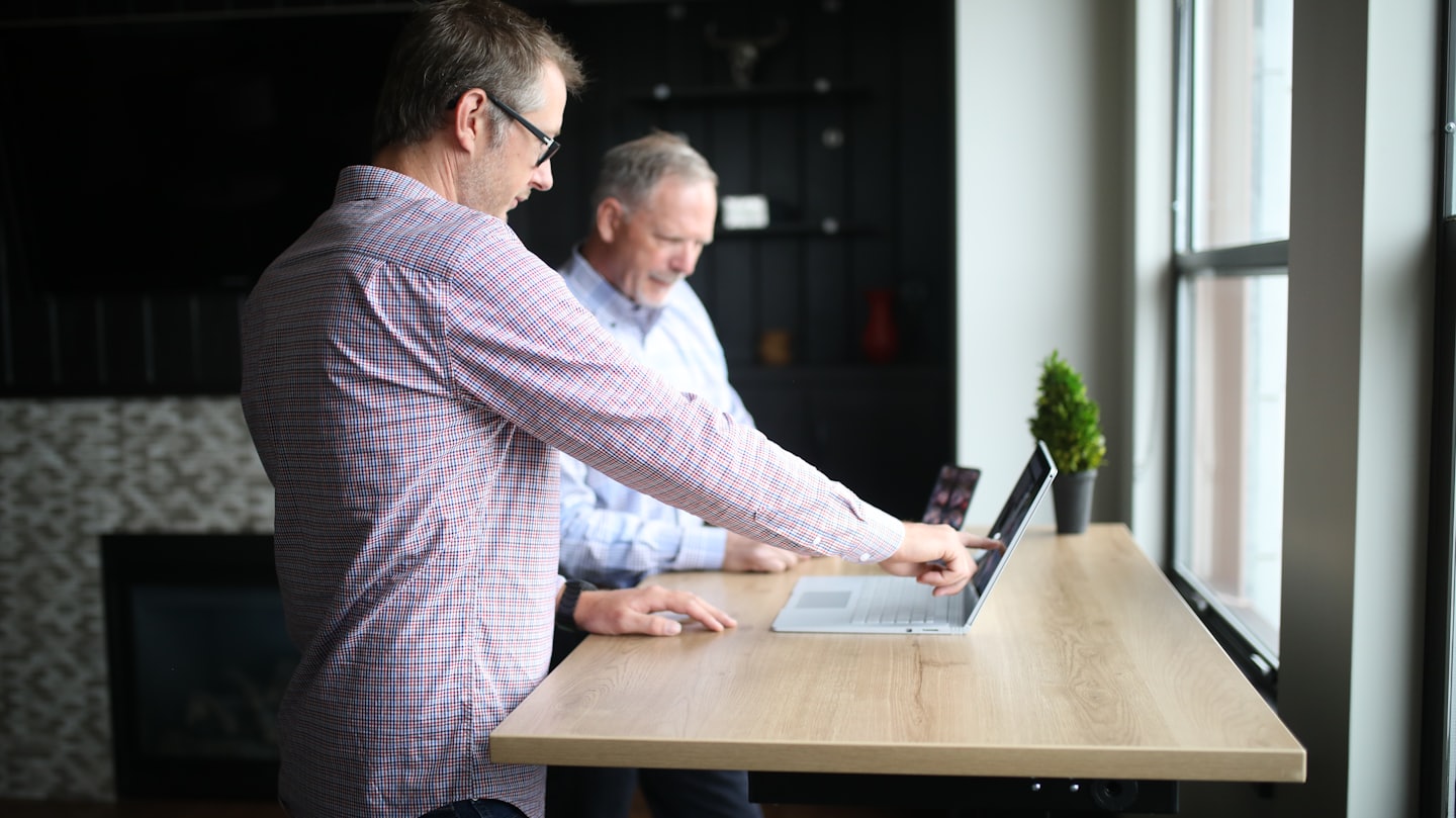 Twee mannen werken samen aan een sta-bureau in een modern kantoor.