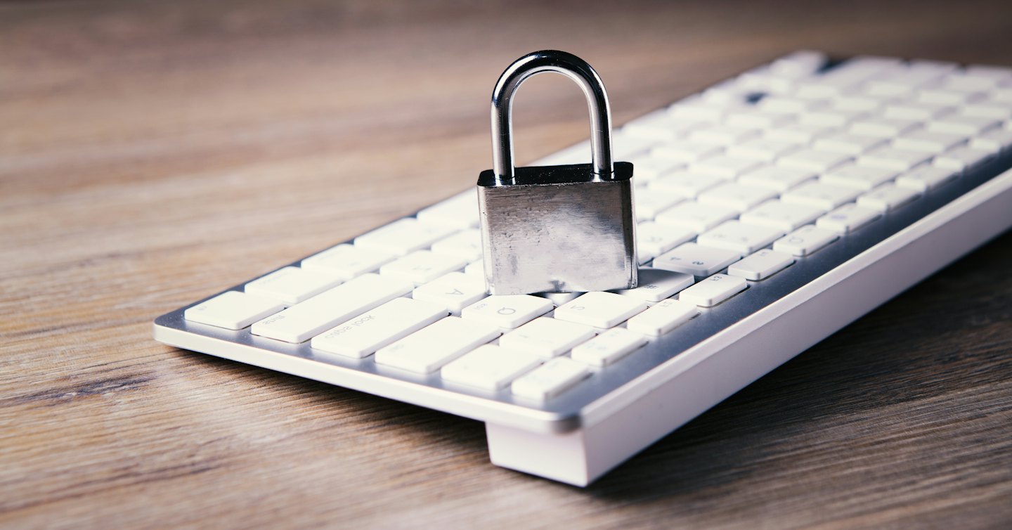 Een zilveren hangslot ligt op een wit computer-toetsenbord.