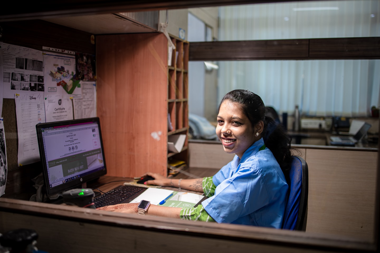 Vrouw in blauw uniform werkt aan haar kantoorcomputer.